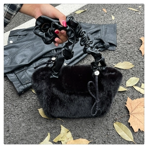 Detail of black faux fur handbag with ruched leather handle on street background