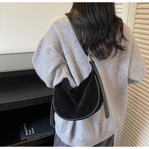 Detail of minimalist black suede hobo bag showing texture and adjustable strap on model