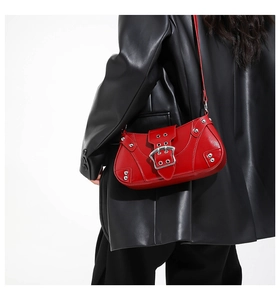Macro view of red patent leather shoulder bag with metallic buckle and silver rivets