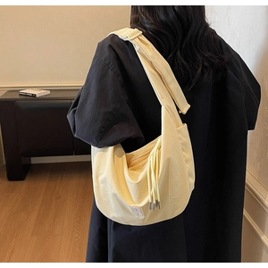 Detail view of a large yellow canvas hobo bag showing adjustable strap and wavy texture