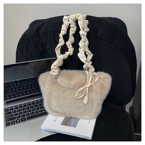 Detail of plush cream faux fur tote bag with stylish ruffled leather handle on chair