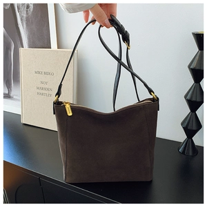 Close-up of golden metal zipper with engraved logo on brown faux suede bucket bag