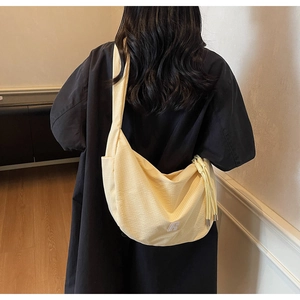 Detail of light yellow waffle fabric crossbody bag with wide strap and logo patch