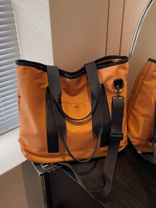 Amber orange canvas tote bag with black straps and adjustable shoulder belt for women