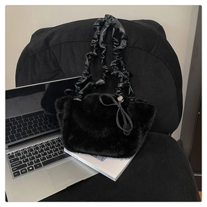Detail of black plush faux fur tote bag with ruched leather strap and bow decoration