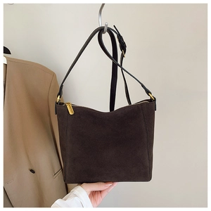 Detail of dark brown suede shoulder bag with smooth golden zipper and premium texture