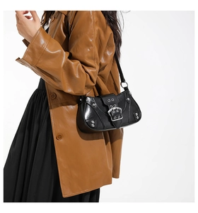 Detail of a black saddle bag with silver rivets and buckles on a female model