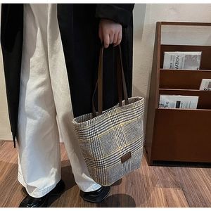 Dettaglio della borsa tote a quadri con manici in pelle marrone e toppa rettangolare