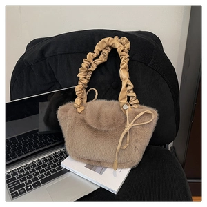 Detail of light brown plush handbag with pleated handle and bow knot on black corduroy