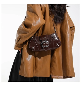Détail d'un sac à bandoulière en cuir verni marron foncé avec rivets et boucle argentée