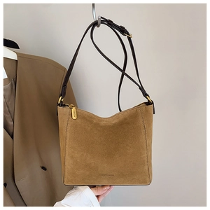 Detail view of brown suede bucket bag featuring polished gold hardware and logo engraving