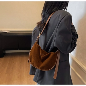 Brown suede crescent bag shown in use with adjustable leather strap and retro style