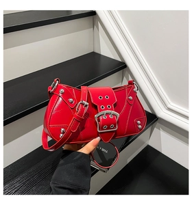 Détail du sac à bandoulière en cuir rouge brillant avec clous et boucles argentées