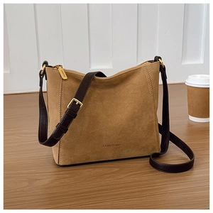 Detail view of brown suede bucket bag featuring leather strap and golden metal hardware
