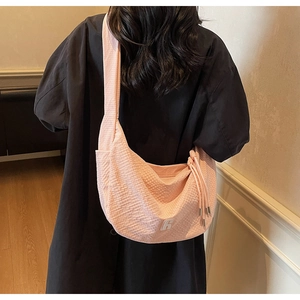 Detail of pink waffle texture crossbody bag shown against a black coat background