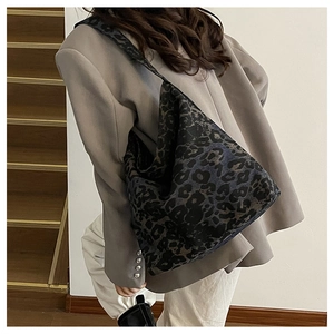 Detail of dark leopard print tote bag with wide shoulder strap in a stylish casual setting