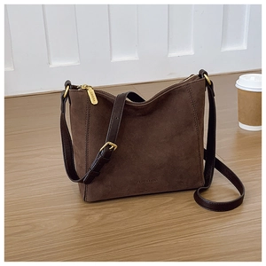 Detailed view of dark brown suede bucket bag with gold zipper and textured leather strap