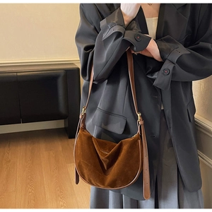 Detail of suede crossbody bag with premium leather trim and golden metal buckle