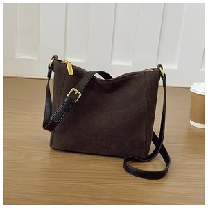 Detail of suede tote bag showing gold zipper closure and textured brown material