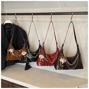 Detail of four glossy faux leather shoulder bags in black, brown, red, and dark coffee colors