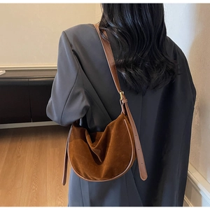 Detailed texture of brown suede hobo bag with adjustable strap and gold metal buckles