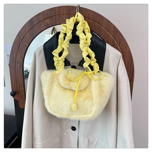 Detail of fluffy yellow faux fur handbag with ruched leather handle on casual jacket