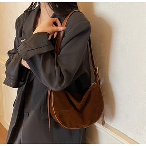 Detail of dark brown suede crescent bag texture and leather strap on shoulder