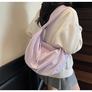 Detail of light purple dumpling bag featuring textured fabric and silver H pendant
