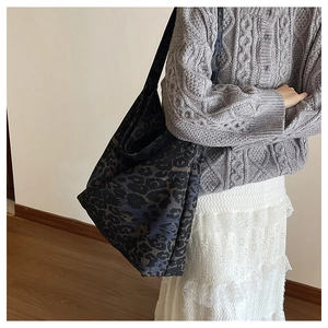 Detailed side view of navy blue leopard print canvas tote bag paired with a grey knit cardigan