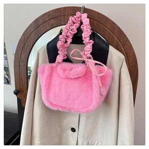 Close-up of pink faux fur handbag featuring ruched handles and ribbon bow detail