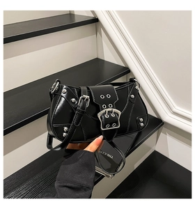 Détail d'un sac à bandoulière noir brillant avec rivets argentés et boucle en métal