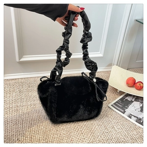 Detail of black faux fur tote bag featuring a long pleated leather strap and side bow detail