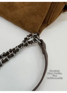 Detail view of caramel brown suede handbag with quilted pattern and metal chain link strap