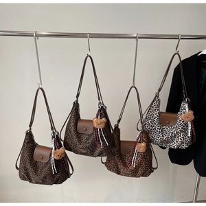 Detail view of leopard print tote bags with brown leather flaps and cute bear charms