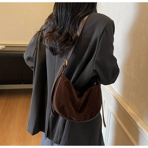 Detail of dark brown suede hobo bag with adjustable strap worn on the shoulder