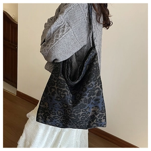 Detail of large leopard print tote bag in dark tones worn over a grey cable knit sweater