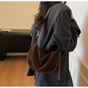 Detail view of a vintage dark brown suede dumpling bag worn by a model in soft lighting