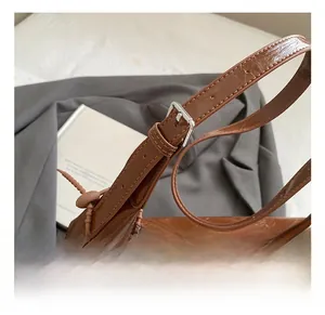Close-up of adjustable strap with silver buckle on brown patent leather chain shoulder bag
