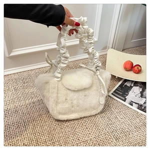 Close-up of white plush handbag with pleated leather handle and soft faux fur texture