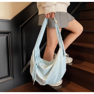 Close-up of light blue waffle texture tote bag featuring side drawstring detail and logo