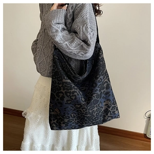 Detailed view of large leopard print tote bag worn over the shoulder by a model