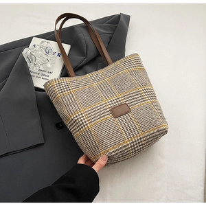 Dettaglio della borsa tote retrò pied-de-poule con manici in pelle marrone e blazer