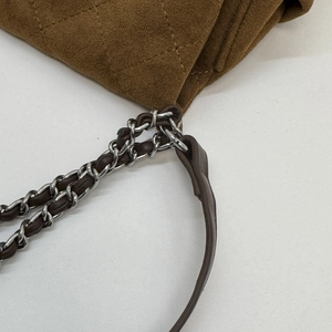 Close-up of quilted dark brown suede handbag with silver chain and leather strap