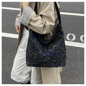 Street style shot of large leopard print tote bag paired with a classic trench coat