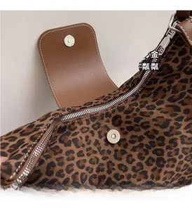 Macro shot of leopard print bag featuring brown leather flap and silver metallic hardware