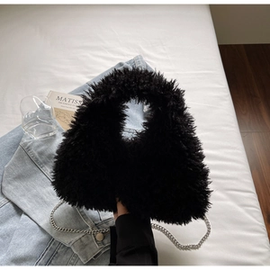 Detailansicht der schwarzen Pelz-Tasche mit Silberkette auf blauem Denim-Stoff