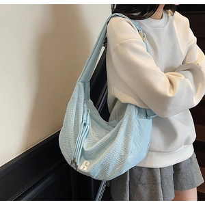 Detail of light blue hobo bag showing pleated texture and silver metal logo accent