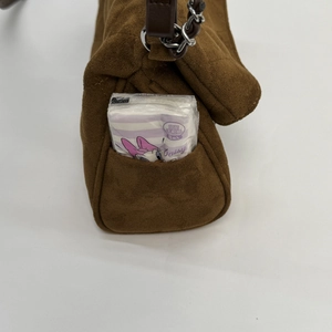 Detail of brown quilted suede shoulder bag with a functional side pocket for small items