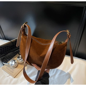 Detail of vintage brown suede dumpling bag with leather strap and gold metal hardware
