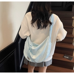 Detail of light blue crossbody bag with drawstring design and R logo on a model
